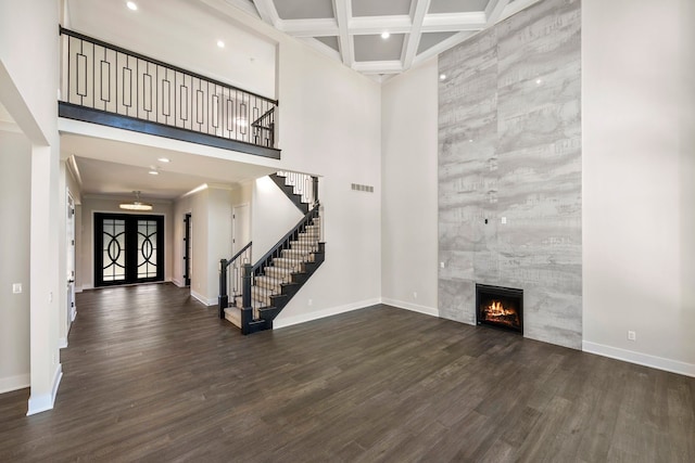 foyer entrance with a tile fireplace, coffered ceiling, french doors, dark hardwood / wood-style floors, and beam ceiling