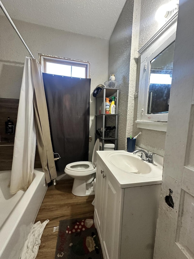 full bathroom featuring hardwood / wood-style floors, vanity, toilet, a textured ceiling, and shower / tub combo