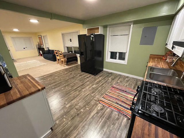 kitchen featuring dark hardwood / wood-style flooring, black fridge with ice dispenser, white cabinetry, and electric panel