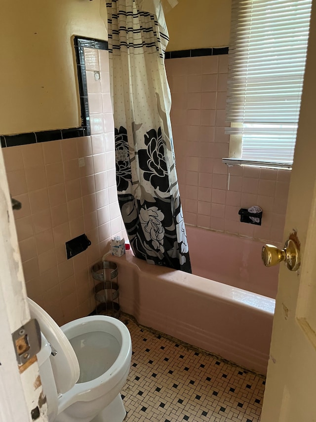 bathroom with tile patterned flooring, toilet, tile walls, and shower / tub combo