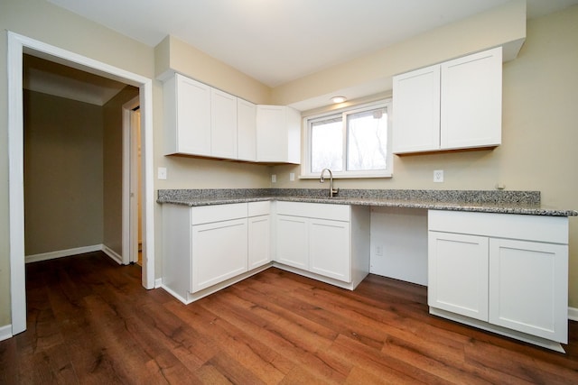 kitchen with stone counters, white cabinetry, sink, and dark hardwood / wood-style floors