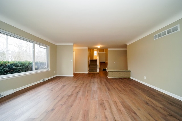 unfurnished living room featuring light hardwood / wood-style floors and a brick fireplace