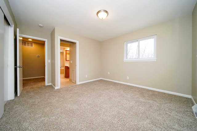 unfurnished bedroom featuring light colored carpet, connected bathroom, and a closet