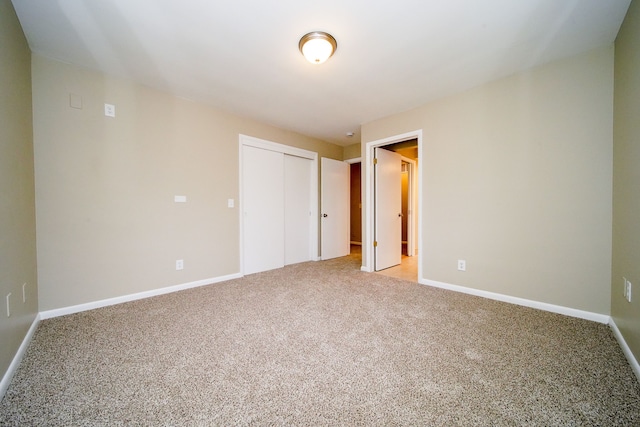 unfurnished bedroom featuring light colored carpet and a closet