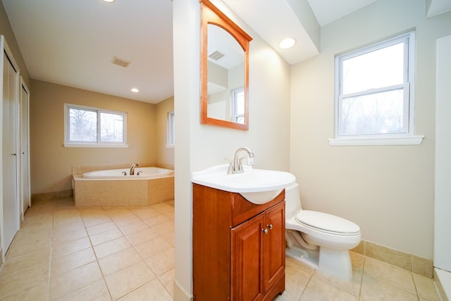 bathroom with vanity, tile patterned flooring, a relaxing tiled tub, and toilet