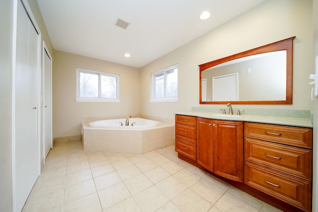 bathroom with tile patterned flooring, vanity, and tiled bath