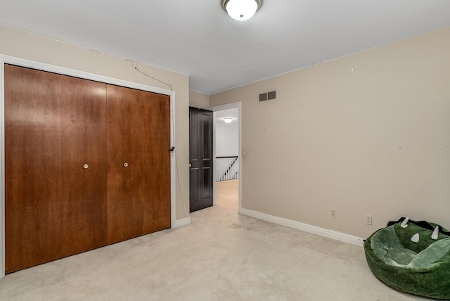 unfurnished bedroom featuring a closet and light colored carpet