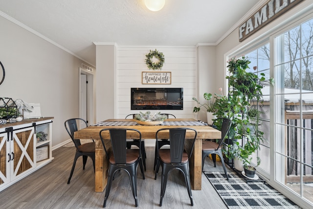 dining space featuring hardwood / wood-style floors, crown molding, and a fireplace