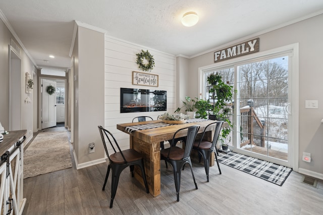 dining room featuring a textured ceiling, hardwood / wood-style flooring, and crown molding