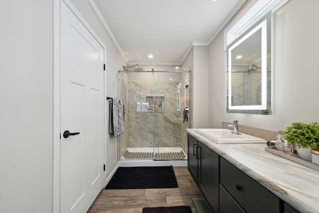 bathroom with hardwood / wood-style flooring, vanity, a shower with shower door, and ornamental molding