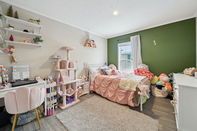 bedroom featuring hardwood / wood-style flooring, ornamental molding, and a textured ceiling