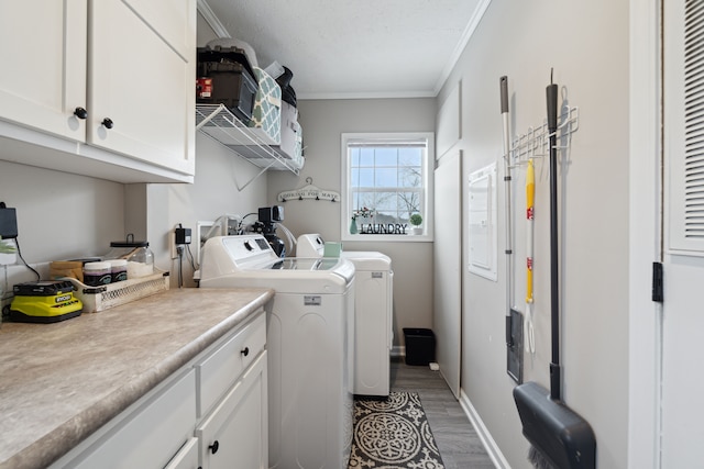 clothes washing area featuring separate washer and dryer, hardwood / wood-style flooring, cabinets, and ornamental molding