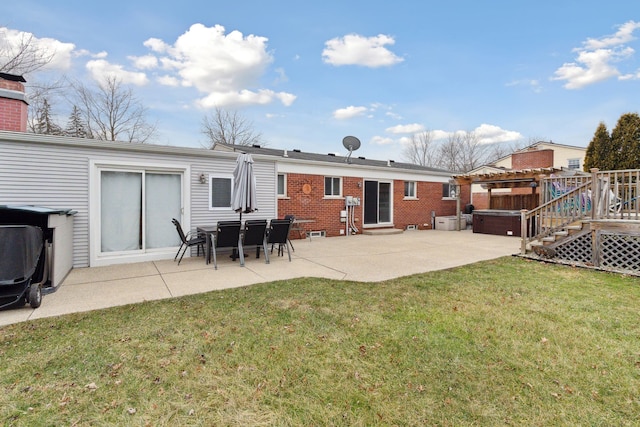 rear view of property featuring a yard, a hot tub, and a patio area