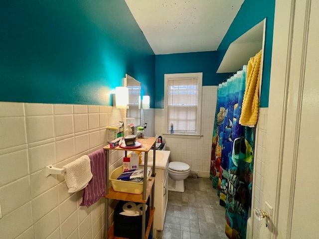 bathroom featuring a shower with shower curtain, toilet, and tile walls