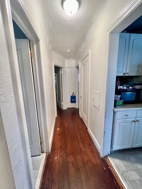 hall with dark hardwood / wood-style floors and a textured ceiling