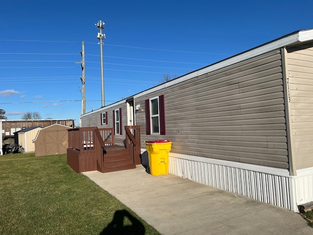 view of side of home with a lawn, a deck, and a storage unit