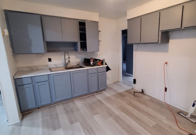 kitchen featuring gray cabinetry, sink, and light wood-type flooring