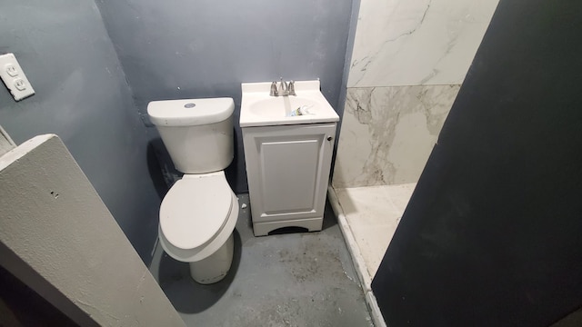 bathroom with vanity, toilet, and concrete floors