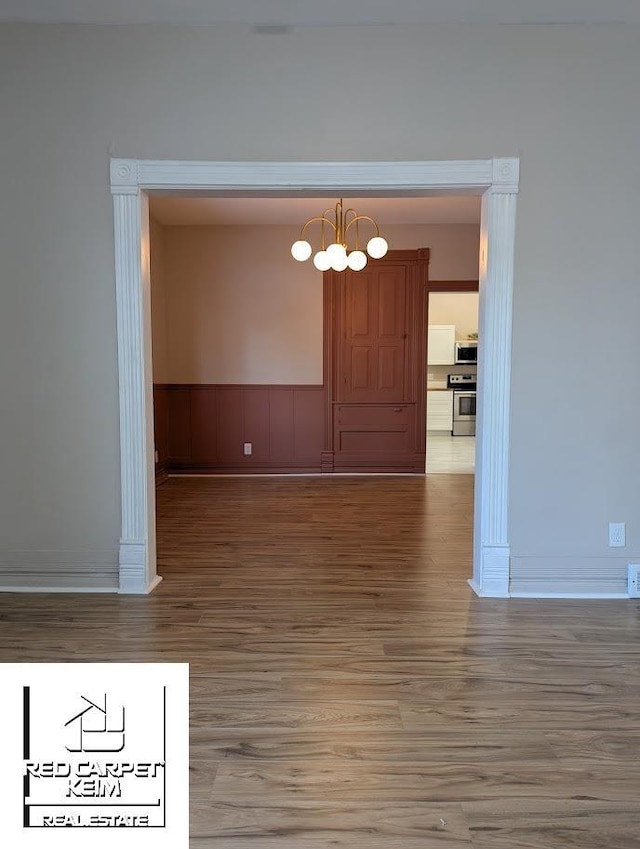 unfurnished dining area featuring wood-type flooring and a chandelier