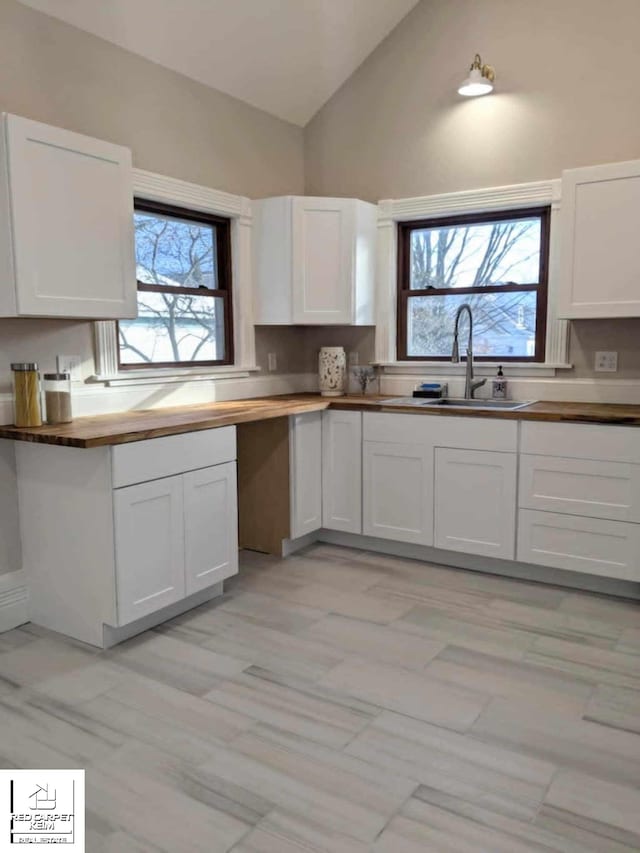 kitchen featuring white cabinets, sink, a wealth of natural light, and vaulted ceiling