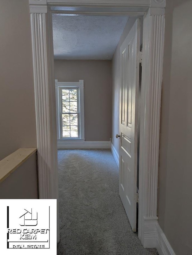 corridor with light colored carpet and a textured ceiling