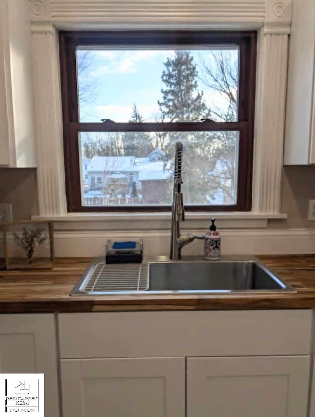 kitchen featuring butcher block counters, white cabinetry, and sink