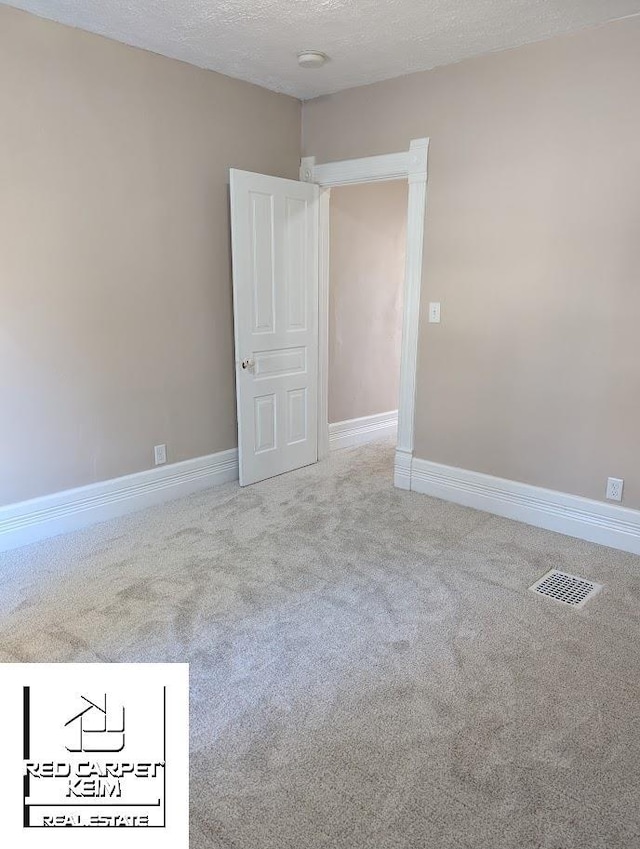 carpeted empty room featuring a textured ceiling