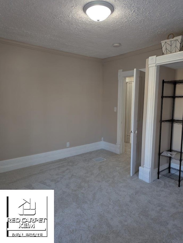 unfurnished bedroom with carpet floors, a textured ceiling, and ornamental molding