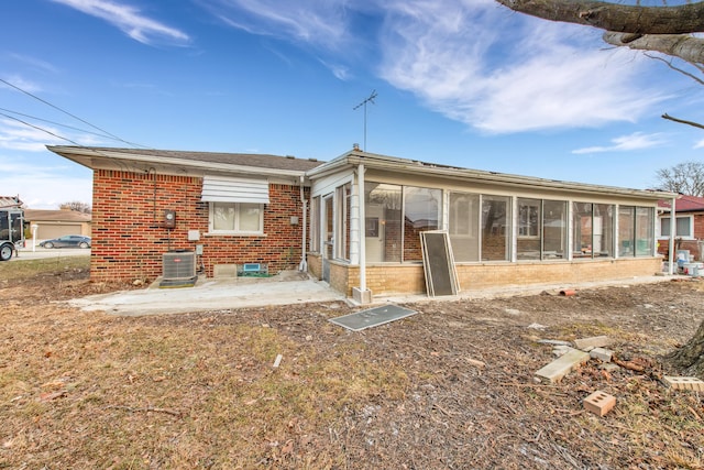 rear view of property with a sunroom, central AC unit, and a patio