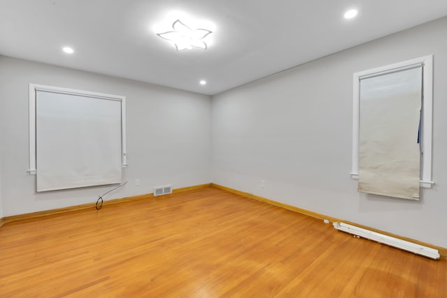 spare room featuring wood-type flooring and baseboard heating