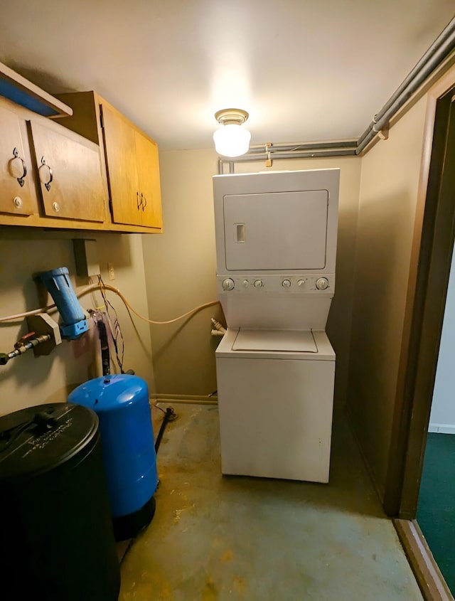 laundry room with cabinets and stacked washer / drying machine