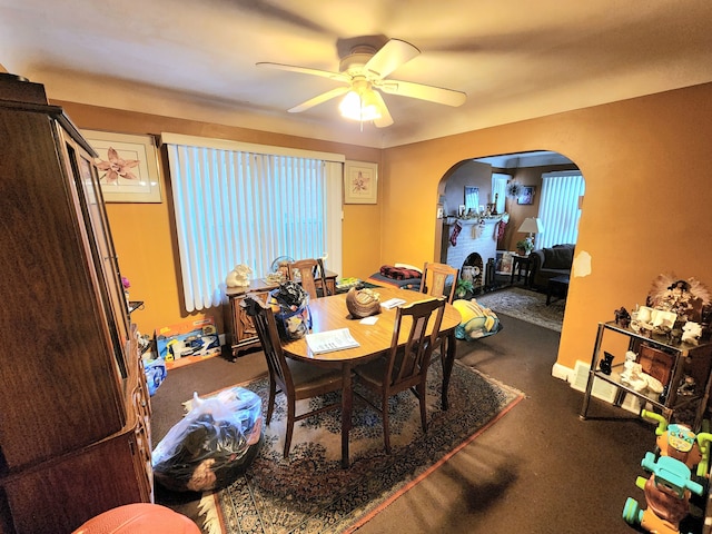 dining area with ceiling fan and a fireplace