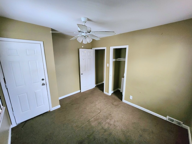 unfurnished bedroom with ceiling fan, two closets, and dark colored carpet