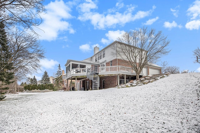 snow covered property featuring a wooden deck, a sunroom, and a garage