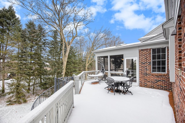 snow covered deck featuring a sunroom