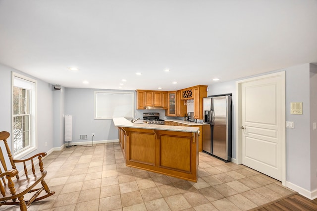 kitchen with glass insert cabinets, light countertops, brown cabinets, recessed lighting, and stainless steel appliances