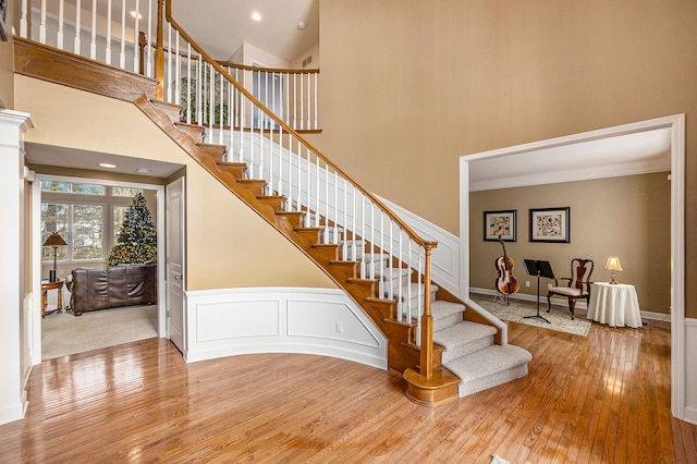 stairs with a towering ceiling and wood-type flooring