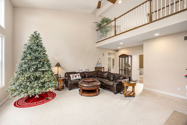 living room featuring carpet flooring, a towering ceiling, ceiling fan, and beamed ceiling