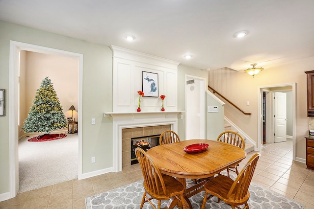 dining area with light carpet and a tile fireplace