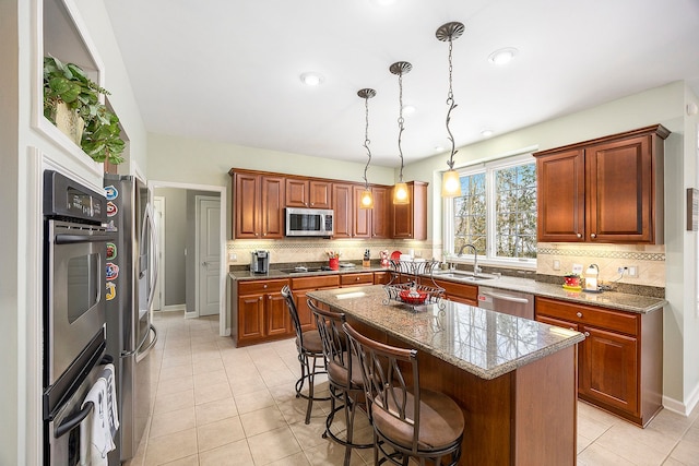 kitchen featuring appliances with stainless steel finishes, sink, pendant lighting, a center island, and a breakfast bar area