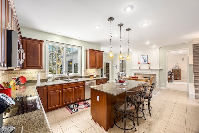 kitchen featuring a center island, sink, hanging light fixtures, light tile patterned flooring, and stainless steel appliances