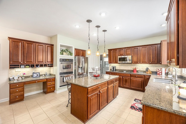 kitchen featuring sink, a center island, dark stone counters, pendant lighting, and appliances with stainless steel finishes