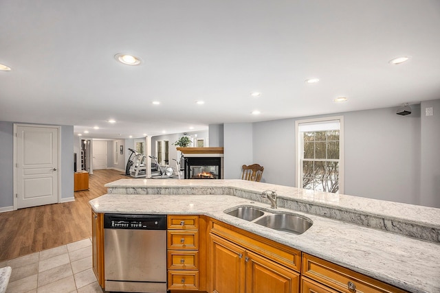 kitchen featuring stainless steel dishwasher, light stone counters, light tile patterned floors, and sink