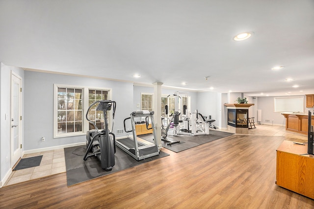 exercise area with ornate columns and light hardwood / wood-style flooring