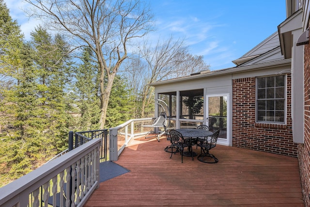 wooden deck with a sunroom and outdoor dining area