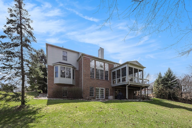 back of house with a lawn, brick siding, a sunroom, and a chimney