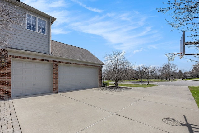 view of property exterior with a shingled roof, concrete driveway, a garage, and brick siding