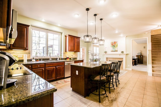 kitchen featuring a fireplace, a kitchen breakfast bar, tasteful backsplash, dishwasher, and a sink