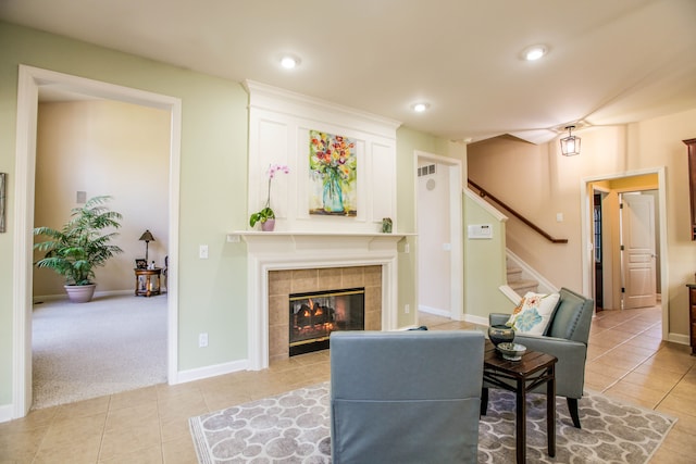 living area featuring visible vents, a tiled fireplace, stairway, and light tile patterned floors