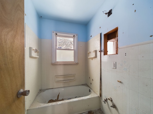 bathroom with a tub and tile walls